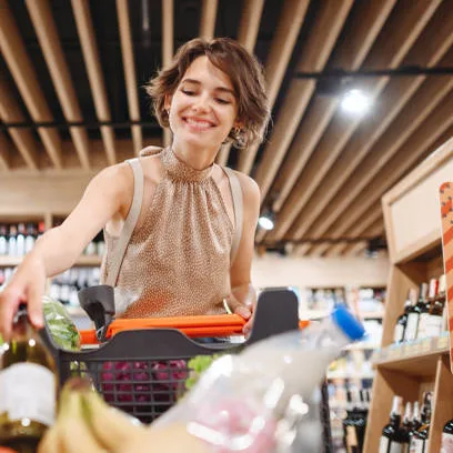 Mulher sorrindo empurrando um carrinho de compras no mercado